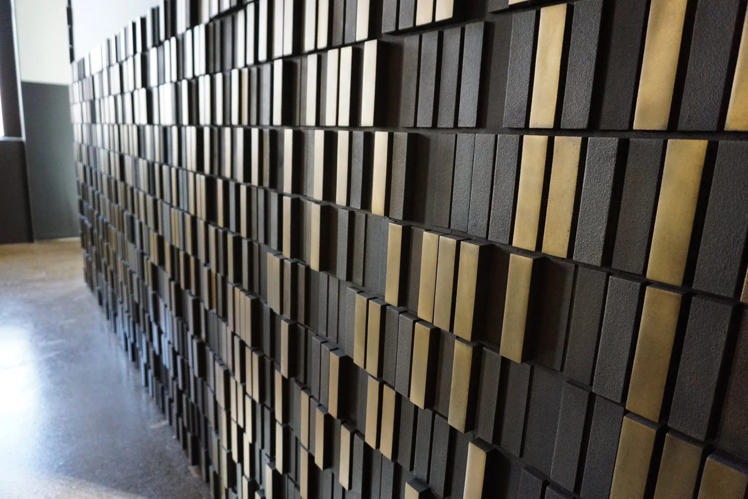 Raking light across the parametric cast aluminum feature wall at Uber Freight headquarters